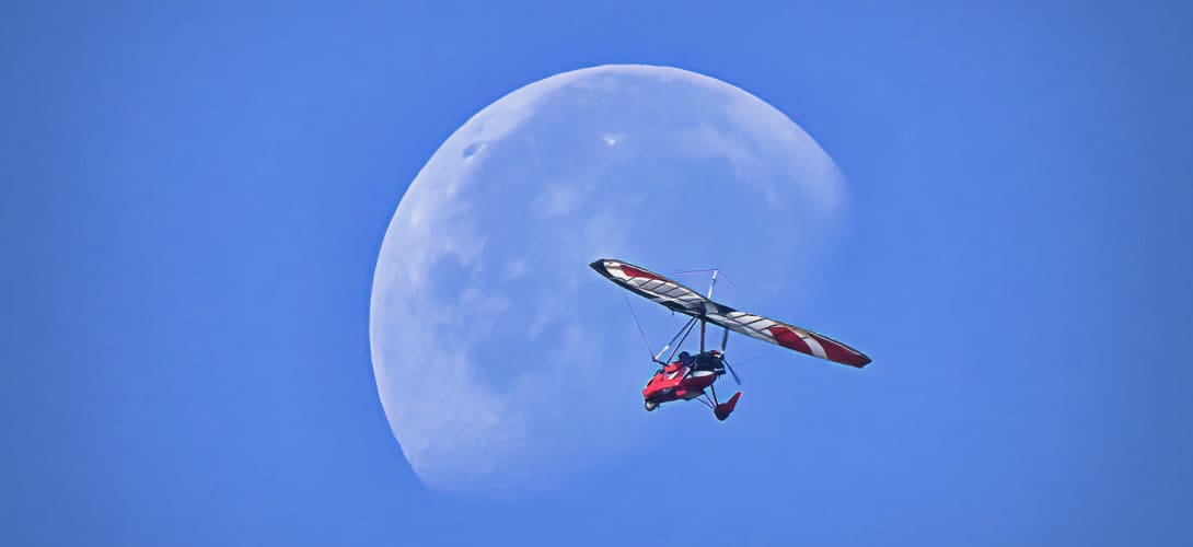An ultralight aircraft flying in front of the moon at Wiley Slough Washington State