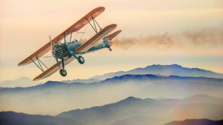 Biplane Flying Low Over Mountains